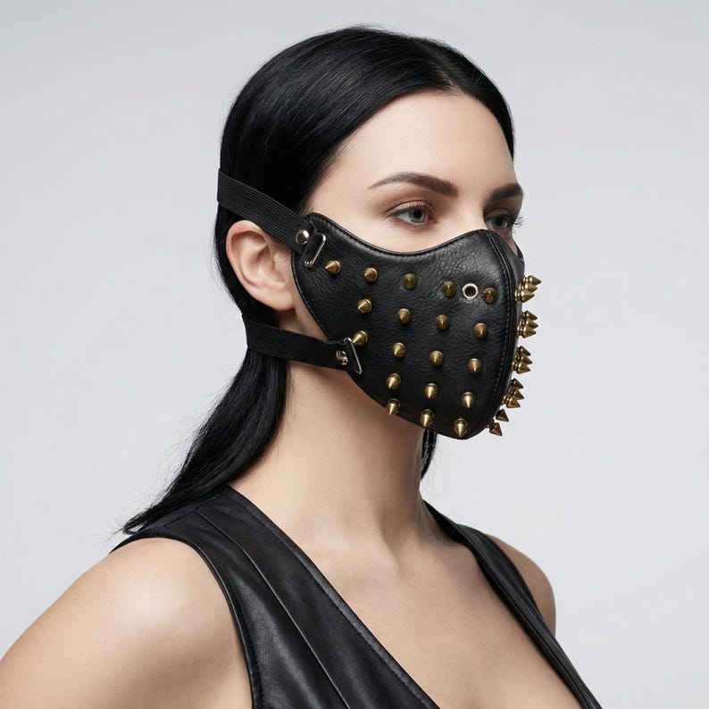 May include: Black leather face mask with gold-colored metal studs and spikes. The mask has an adjustable elastic strap and leather straps with metal buckles. The mask covers the nose and mouth area.