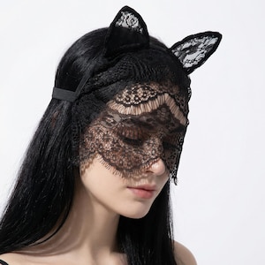 May include: Black lace cat ear mask with a matching lace eye covering. The mask has a delicate floral pattern and is secured with a thin elastic band. The cat ears are made of a soft, velvety material.