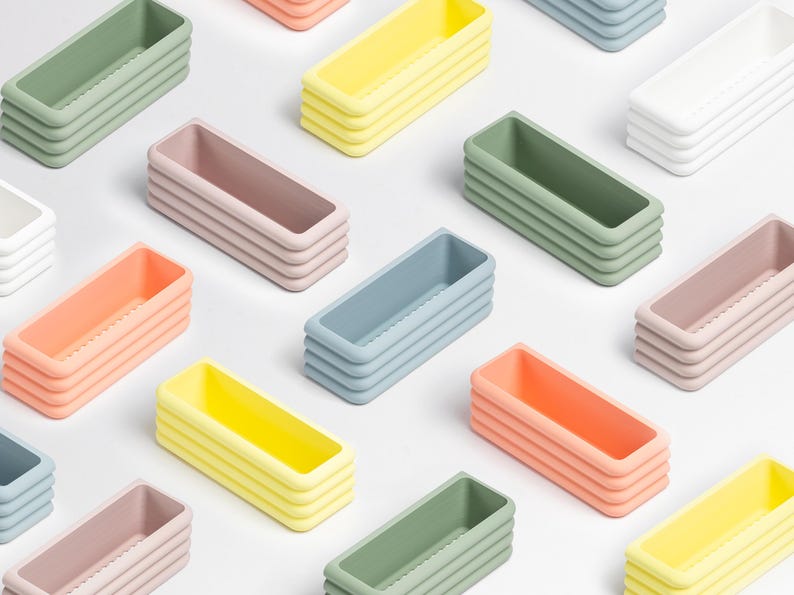 Puede incluir: Una colecci&oacute;n de bandejas de almacenamiento rectangulares dispuestas en un patr&oacute;n de cuadr&iacute;cula. Cada bandeja presenta un dise&ntilde;o de pared exterior acanalado de varias capas y viene en varios colores pastel, incluyendo verde salvia, amarillo p&aacute;lido, rosa suave, blanco y azul claro.