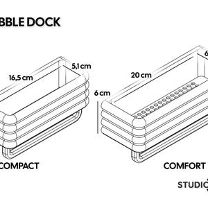 Może przedstawiać: Dwa czarno-białe rysunki liniowe organizer&oacute;w Bubble Dock z etykietami Compact i Comfort. Model Compact ma wymiary 16,5 cm na 5,1 cm na 6 cm. Model Comfort ma wymiary 20 cm na 6,7 cm na 6 cm i posiada perforowaną podstawę. Dołączone logo Studio 23.