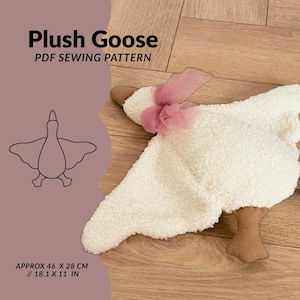 Op de afbeelding: Een witte pluche gans van gestructureerde, sherpa-achtige stof, voorzien van een roze organza lint om de nek en bruine stoffen voeten. De afbeelding bevat de tekst Plush Goose PDF SEWING PATTERN en afmetingen van 46 x 28 cm.