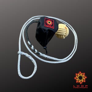 Puede incluir: Un juego de accesorios de fuego con una bolsa negra con un logotipo rojo y amarillo, una bola beige y una cuerda trenzada blanca. La cuerda está en bucle y anudada. El logotipo dice "LOOP FIRE PROPS".