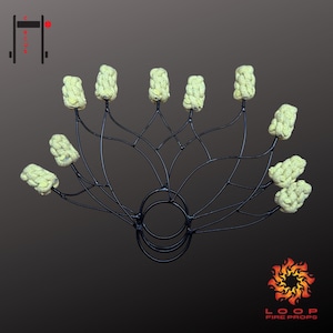 Puede incluir: Accesorio de fuego de metal negro con múltiples mechas amarillas claras. El accesorio tiene una base circular con brazos curvos que se extienden hacia afuera, cada uno sosteniendo una mecha. El logotipo "LOOP FIRE PROPS" es visible.