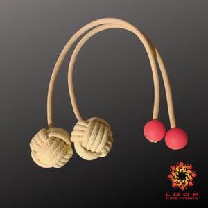 Puede incluir: Un par de accesorios de poi de fuego con asas de cuerda beige y cabezas anudadas, y dos bolas de goma rojas. Los accesorios están diseñados para el rendimiento y presentan el logotipo "LOOP FIRE PROPS" en la esquina inferior derecha.