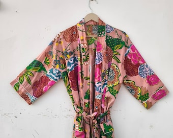 May include: A floral print robe in shades of pink, green, and brown hangs on a wooden hanger. The robe features a tie waist and white trim along the edges. The design includes large floral patterns and a mix of colors.