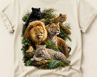 Può includere: T-shirt color crema con una vivace illustrazione di un leone, una tigre, un leopardo e una pantera nera in mezzo a una vegetazione lussureggiante. La maglietta ha le maniche arrotolate e il logo Comfort Colors.