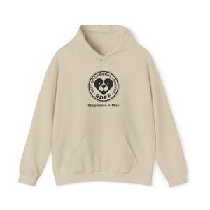 May include: Cream-colored hoodie with a front pocket and drawstring hood. The front features a black circular graphic with a dog face inside a heart, the text "BEST DOG FRIENDS FOREVER" and "BDF", and the names "Stephanie + Max".