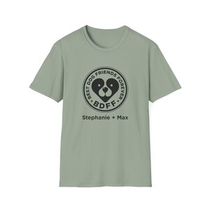 May include: Sage green t-shirt with a black circular graphic that reads "BEST DOG FRIENDS FOREVER" around a dog face design. Below the graphic is "BDF" and the names "Stephanie + Max".