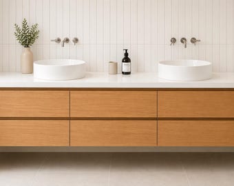 May include: A modern bathroom vanity with a light wood finish. The vanity features six drawers and a white countertop with two round, white sinks. The wall is white with vertical tile, and the faucets are silver.