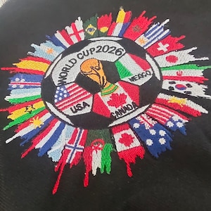 May include: Embroidered patch featuring a soccer ball design with the text "WORLD CUP 2026". The soccer ball is surrounded by flags of various countries. The flags of USA, Canada, and Mexico are prominently displayed.