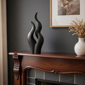 May include: A black, abstract sculpture with a flowing, curved design. The decorative piece is made of a smooth material and stands on a dark wood surface. The sculpture is a modern home decor accent.
