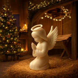 Op de afbeelding: Een crèmekleurig engelenbeeldje met een halo en vleugels, knielend met gevouwen handen in gebed. De engel staat tegen een achtergrond van een kerstboom en warme verlichting, wat duidt op een vakantiethema.