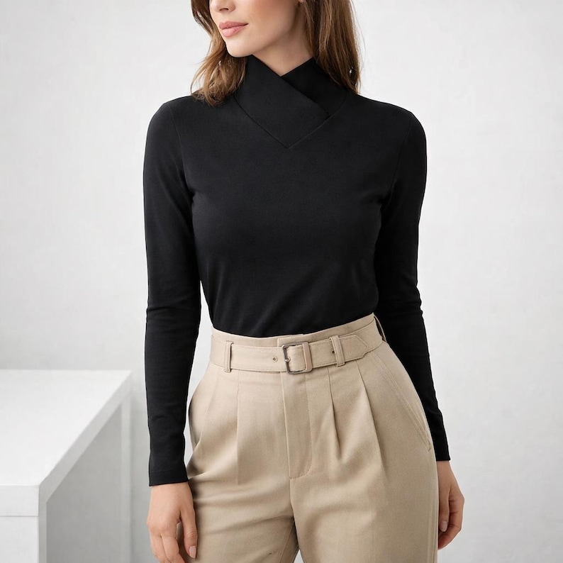 May include: A black long-sleeve top with a unique, folded neckline. The top is paired with beige pleated pants and a matching belt. The outfit is simple and elegant, suitable for various occasions.