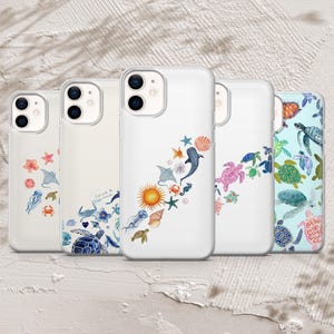 May include: A selection of white phone cases adorned with marine-themed illustrations. The cases showcase watercolour designs of sea creatures, including turtles, jellyfish, starfish, and rays. Some cases have text. The colour palette includes blues, pinks, greens, and oranges.