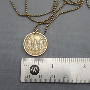 May include: Gold necklace with a Greek drachma coin pendant featuring a phoenix and the text "&Epsilon;&Lambda;&Lambda;&Eta;&Nu;&Iota;&Kappa;&Eta; &Delta;&Eta;&Mu;&Omicron;&Kappa;&Rho;&Alpha;&Tau;&Iota;&Alpha; 1973".