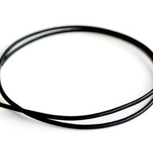 May include: A black leather cord necklace with a silver clasp.