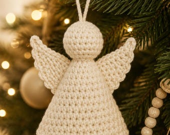 May include: A cream-colored crocheted angel ornament featuring a round head, a conical body, and two triangular wings. The ornament includes a matching yarn loop at the top for hanging, with a scalloped edge detail along the base of the dress.
