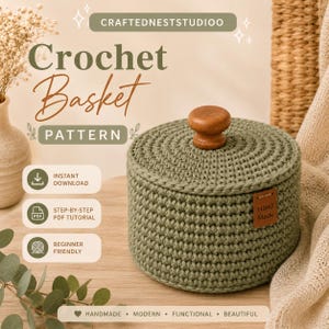 May include: A sage green round crochet basket with a matching lid and a small wooden knob handle. A brown leather-like tag labeled Hand Made is attached to the side. Text on the image includes CRAFTEDNESTSTUDIOO, Crochet Basket PATTERN, INSTANT DOWNLOAD, STEP-BY-STEP PDF TUTORIAL, BEGINNER FRIENDLY, and HANDMADE MODERN FUNCTIONAL BEAUTIFUL.