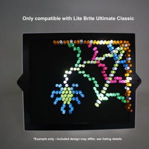 May include: A black Lite Brite board displaying a colourful spider and web design created with small, illuminated pegs. The text at the top reads "Only compatible with Lite Brite Ultimate Classic". The bottom text reads "*Example only - included design may differ, see listing details".