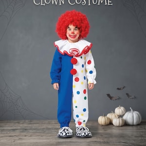 Könnte beinhalten: Ein Halloween-Clownkostüm für Kleinkinder mit einer roten Lockenperücke, einem weißen Rüschenkragen mit rotem Rand und einem Overall, der ein einfarbig blaues Bein und ein weißes Bein mit bunten Punkten sowie zwei rote Pompons auf der Brust hat.