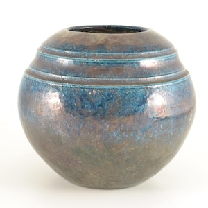 Może przedstawiać: Okrągły, ceramiczny wazon z niebiesko-brązowym metalicznym szkliwem. Wazon ma szeroki, zaokrąglony korpus i wąski otwór u góry. Trzy poziome pasma otaczają górną część. Dekoracyjny przedmiot do domu.