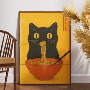 May include: A framed art print featuring a black cat eating noodles from an orange bowl. The cat has large yellow eyes and is set against a yellow background. The print has Japanese text in the upper right corner.