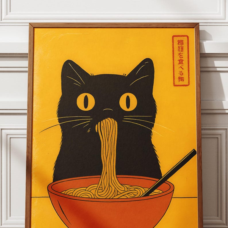 May include: A framed poster featuring a black cat eating noodles from an orange bowl. The cat has large yellow eyes and is set against a yellow background. Japanese text is in the upper right corner. The poster has a wooden frame.