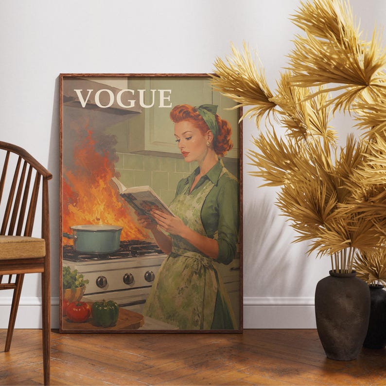 Peut inclure: Une affiche encadr&eacute;e de style vintage avec le mot "VOGUE" en haut, repr&eacute;sentant une femme dans une cuisine lisant un livre tandis qu'une casserole d&eacute;borde sur la cuisini&egrave;re. La femme porte une robe et un tablier verts. Une chaise et un vase de plantes s&eacute;ch&eacute;es sont au premier plan.