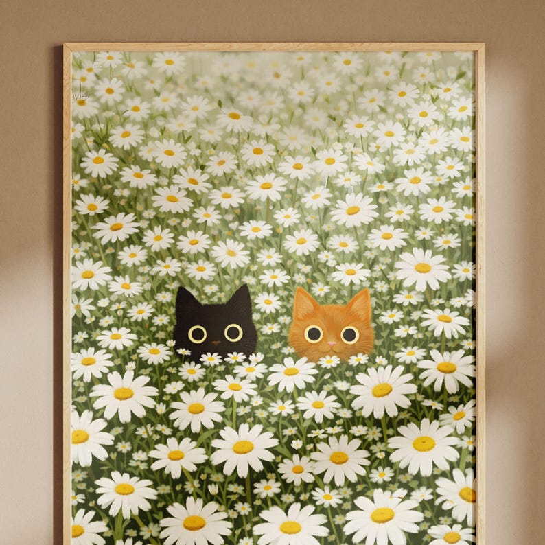 Puede incluir: Una impresi&oacute;n art&iacute;stica enmarcada que presenta dos caras de gato asom&aacute;ndose desde un campo de margaritas blancas con centros amarillos y follaje verde. Un gato es negro, el otro es naranja. La obra de arte tiene un tema caprichoso inspirado en la naturaleza.