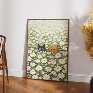 Puede incluir: Una impresi&oacute;n art&iacute;stica enmarcada que representa un campo de margaritas blancas con centros amarillos. Dos caras de gato, una negra y otra naranja, asoman entre las flores. La obra de arte est&aacute; en un marco de madera marr&oacute;n y contra una pared blanca.