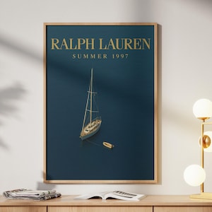 May include: A framed print featuring a sailboat on a deep blue sea. The text "RALPH LAUREN SUMMER 1997" is displayed in gold lettering at the top. The print is in a wooden frame, evoking a sense of classic nautical style.