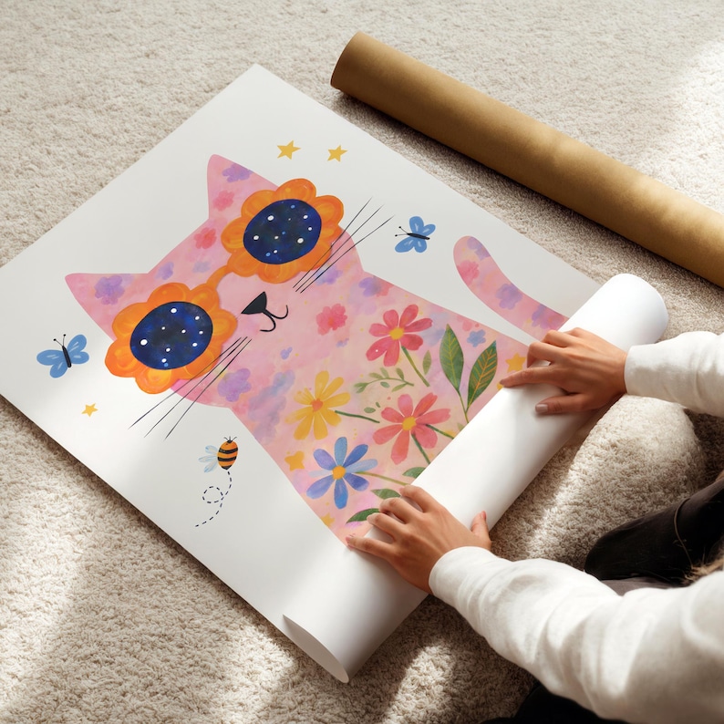 May include: A whimsical art print featuring a pink cat wearing flower-shaped sunglasses with a starry design. The cat is decorated with colorful flowers and butterflies. A rolled-up print and a brown tube are also visible.