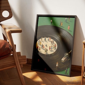 Puede incluir: Una impresi&oacute;n art&iacute;stica enmarcada representa un disco de vinilo con figuras en miniatura bailando sobre su superficie. El fondo es verde y el disco es negro. La impresi&oacute;n est&aacute; en un marco negro y se apoya contra una pared.
