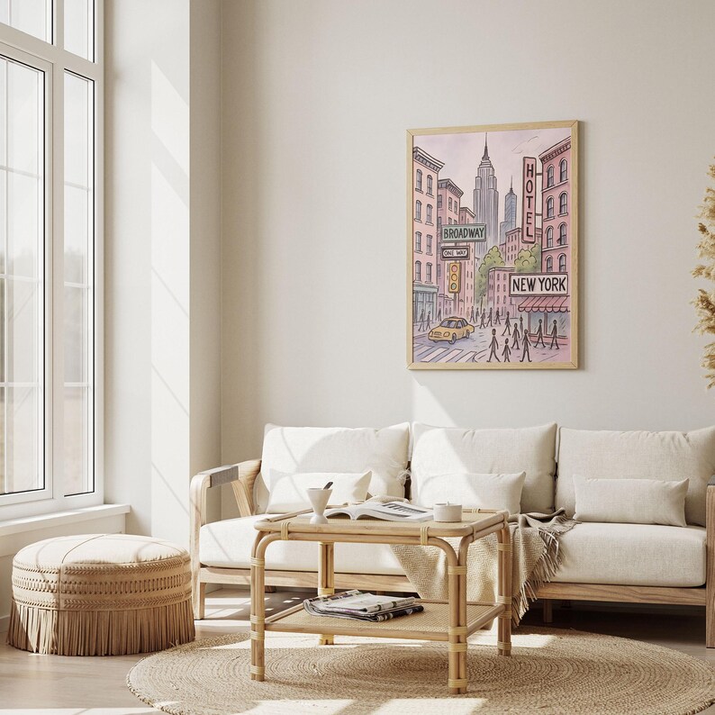 May include: A framed art print depicting a New York City street scene. The artwork features buildings, street signs, a yellow taxi, and pedestrians. The words "Broadway", "Hotel", and "New York" are visible. The color palette includes pink, blue, and yellow.