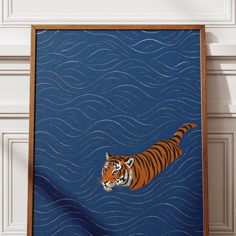 Puede incluir: Una impresi&oacute;n art&iacute;stica enmarcada que representa un tigre nadando en agua azul con patrones de olas blancas. El tigre tiene rayas naranjas y negras y mira hacia la izquierda. El marco es de madera marr&oacute;n.
