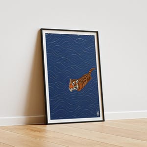 Puede incluir: L&aacute;mina art&iacute;stica enmarcada que representa un tigre nadando en un mar azul con patrones de olas blancas. El tigre tiene rayas naranjas y negras. La impresi&oacute;n est&aacute; en un marco negro.