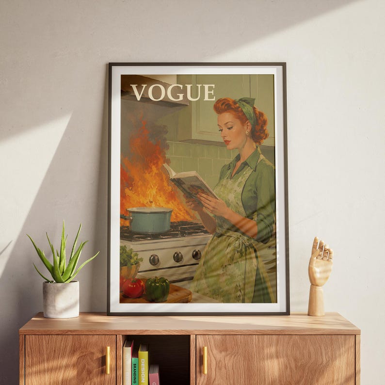 Peut inclure: Reproduction d'une couverture de magazine Vogue de style vintage encadr&eacute;e. L'image montre une femme lisant un livre de cuisine dans une cuisine en feu. Le logo Vogue est en haut. Palette de couleurs : verts, oranges et blancs.