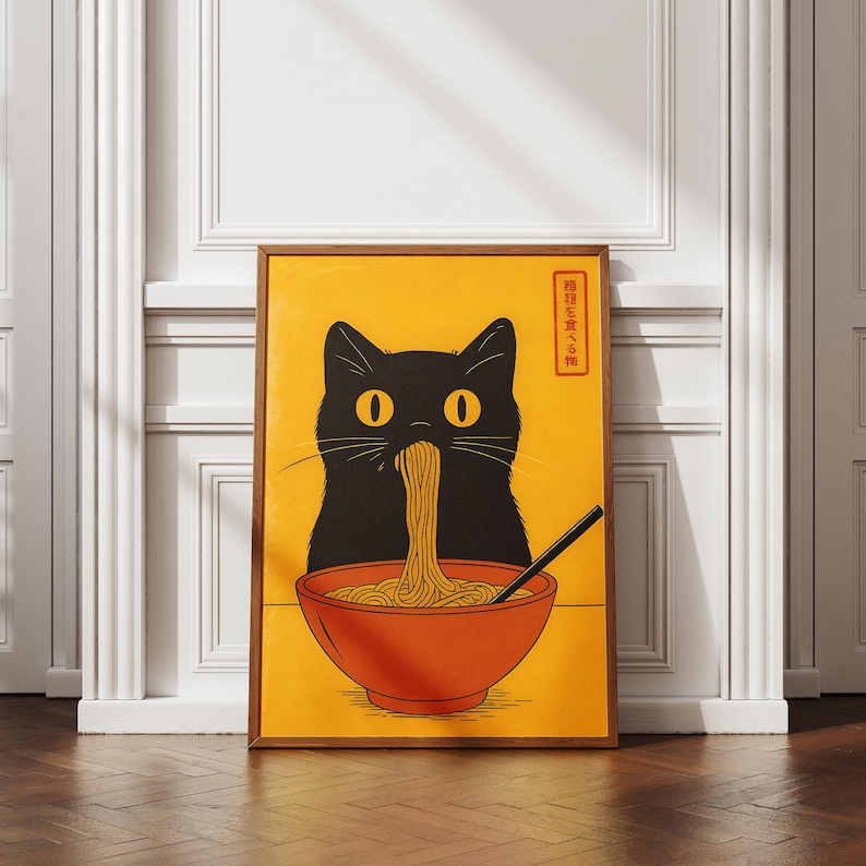 May include: A framed art print featuring a black cat eating noodles from a red bowl. The cat has large yellow eyes and is set against a yellow background. A pair of chopsticks is in the bowl. Japanese text is in the upper right corner.