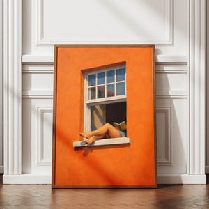May include: A framed artwork depicts a person relaxing in a window, reading a book. The window is set in an orange wall, with a white frame and a view of the sky. The artwork is framed in a brown wooden frame.