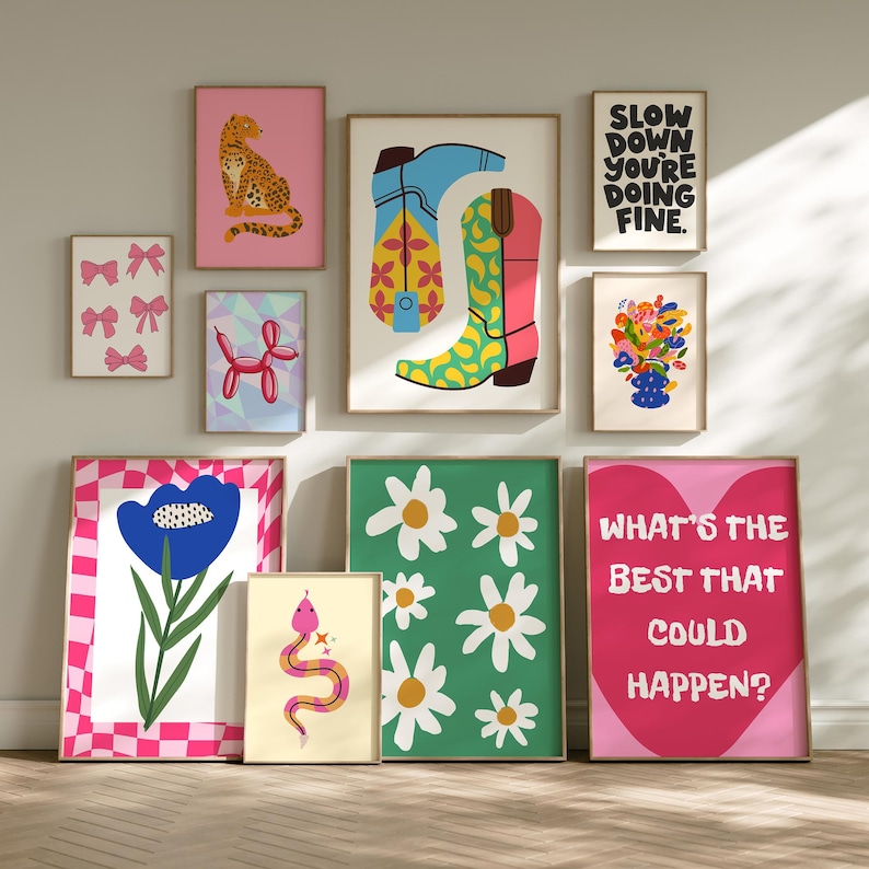 May include: A collection of framed art prints with colorful illustrations. The prints feature a variety of designs, including a leopard, cowboy boots, bows, flowers, a balloon animal, a snake, and text that reads "SLOW DOWN YOU'RE DOING FINE" and "WHAT'S THE BEST THAT COULD HAPPEN?"