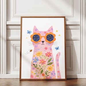 May include: A framed art print featuring a pink cat with flower-shaped sunglasses. The cat is decorated with floral patterns and a bouquet of colorful flowers. Butterflies, stars, and a bee are also included in the design. The artwork is set against a white background.