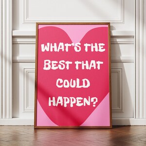 May include: A framed print with the text "WHAT'S THE BEST THAT COULD HAPPEN?" in white, set against a pink heart shape on a light pink background. The wooden frame adds a classic touch to the motivational artwork.