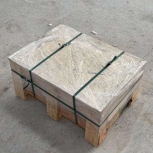 K&ouml;nnte beinhalten: Eine rechteckige Holzpalette mit einem verpackten Paket. Das Paket ist mit gr&uuml;nen Gurten und klarer Plastikfolie gesichert. Die Palette besteht aus hellem Holz und steht auf einem Betonboden.