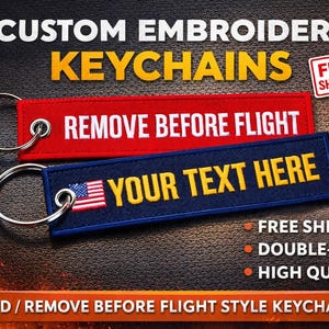 May include: Custom embroidered keychains in red and navy blue. One keychain reads "REMOVE BEFORE FLIGHT" in white, the other says "YOUR TEXT HERE" with an American flag. Both have silver keyrings.