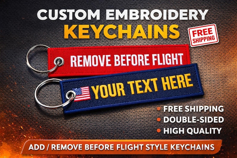 May include: Custom embroidered keychains in red and navy blue. One keychain reads "REMOVE BEFORE FLIGHT" in white, the other says "YOUR TEXT HERE" with an American flag. Both have silver keyrings.