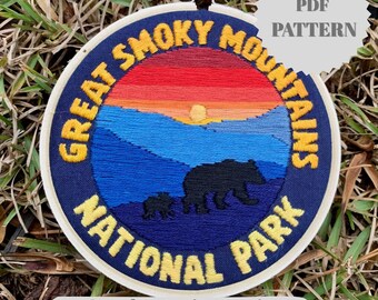 May include: Embroidered patch featuring a Great Smoky Mountains National Park design. The circular patch has a navy blue background with yellow text and a colorful sunset scene. Includes a bear and cub silhouette. Text reads "PDF PATTERN" and "Step-by-step instructions with color guide."