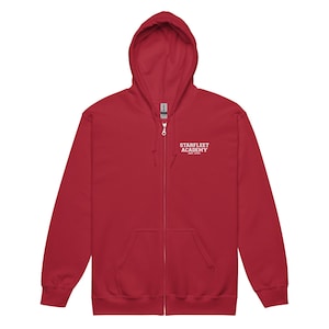 May include: A red zip-up hoodie with a hood and front pockets. The white text "STARFLEET ACADEMY" is printed on the upper chest. The hoodie is made of a soft material.