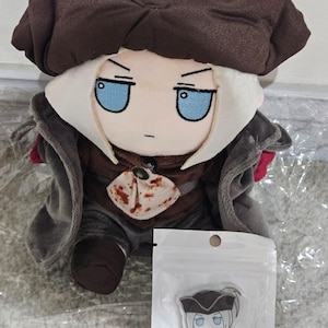 May include: A plush doll with a brown hat and outfit, white hair, and blue eyes. The doll has a stern expression. A clear plastic package with a small character illustration that says "Fumo Maria" is in front of the doll.