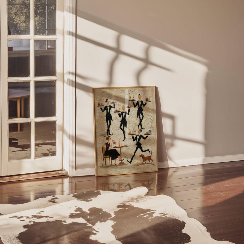 May include: Framed artwork depicting stylized figures in a restaurant setting. The artwork features waiters in black suits carrying trays, a woman seated at a table, and a dog. The frame is a light brown color.