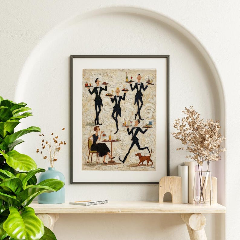 May include: A framed art print depicting a restaurant scene with waiters in black tuxedos carrying trays. A woman in a black dress sits at a table, and a dog runs alongside a waiter. The artwork has a textured background and is displayed on a shelf.